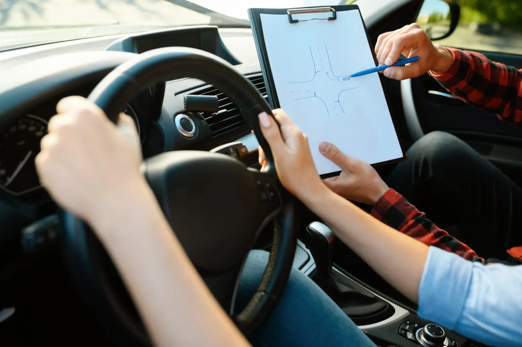Instructor talking a learner through a junction on a checklist during a driving lesson